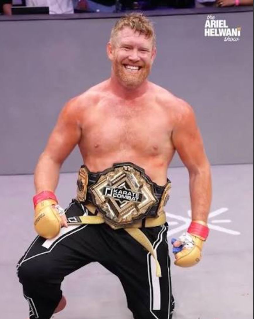 Sam Alvey posing in a ring with a Karate Combat championship belt
